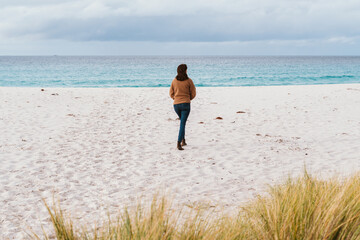 Fototapeta na wymiar Woman walking on the Sandy Beaches of Taylors Beach in Tasmania