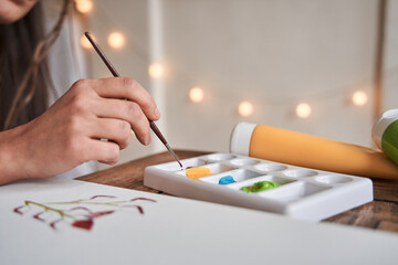 Caucasian creative woman illustrator holding brush and drawing artwork for the future clients