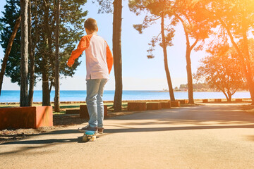 Boy riding skateboard outdoors in summer day in the road, Child learns to ride a penny board,...