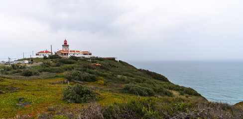 Fototapeta na wymiar Famous tourist attraction the westernmost point of the Europe where tourists walk and take pictures.View near of Cabo da Roca lighthouse. Majestic coastline looking the Atlantic Ocean