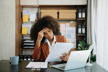 African business woman is stressed, bored, and overthinking from working on a tablet at the office.