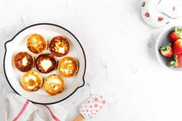 Cottage cheese pancakes, cheesecakes, ricotta fritters in a frying pan with fresh strawberries. Healthy and delicious breakfast for Valentine's Day. Top view, a place to copy.