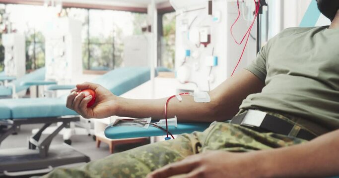 Close Up Of Hand Of Black Army Soldier With Attached Catheter In Military Hospital. Brave African Male Troop Sqeezing Red Ball To Pump Blood Through Tubing Into Bag. Man Donating To Wounded Comrades.