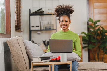 African American female student sitting on the sofa in her home online class.