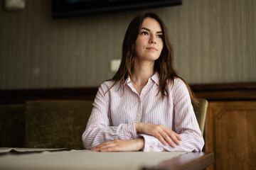 Young beautiful brunette woman sit in coffee shop cafe restaurant indoors.