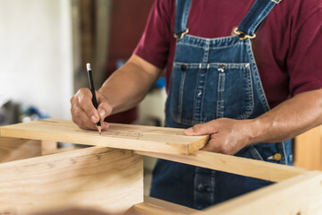 Close up carpenter using pencil marking on wood plank in carpentry workshop, Carpenter and...