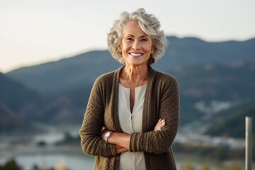 Environmental portrait photography of a glad mature woman wearing a chic cardigan against a scenic mountain overlook background. With generative AI technology