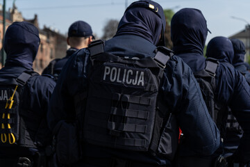 Polish Police officers keeping order in manifestation protest. Riot control squad, policeman on duty controlling a demonstration. Letters in Polish language, Policja means Police. © Longfin Media