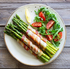 Asparagus baked with bacon and arugula and tomato salad. Healthy eating. Diet.