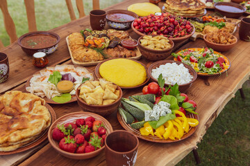Homemade Romanian Food with grilled meat, polenta and vegetables Platter on camping. Romantic traditional moldavian food outside on the wood table.