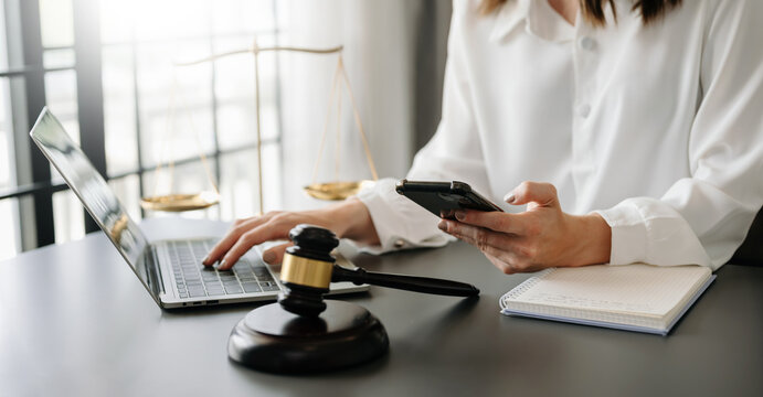 justice and law concept.Male judge in a courtroom  the gavel, working with smart phone and laptop and digital tablet computer on wood table in morning light ..