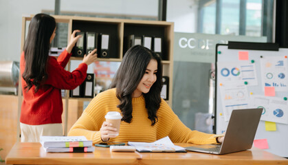 Two Asian businesswoman discuss investment project working and planning strategy with tablet laptop computer in office room.