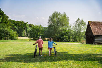 Back view of the senior father and his daughter bicycling together in the park
