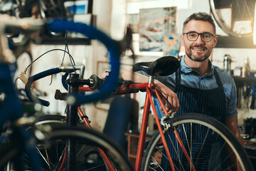Fototapeta na wymiar Portrait, happy and repair man in bicycle shop for working in store, cycling workshop and startup. Confident bike mechanic, small business owner and mature male technician with glasses in Australia
