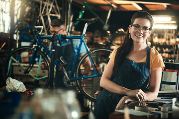 Portrait, mechanic and smile of woman in bicycle shop, repair store or cycling workshop. Face, bike...