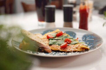 Slice of pizza with cherry tomato, cheese and basil leaf on a blue plate, selective focus.