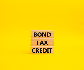 Bond Tax Credit symbol. Concept word Bond Tax Credit on wooden blocks. Beautiful yellow background. Business and Bond Tax Credit concept. Copy space