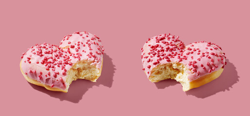 Bitten heart shaped donut with glaze on pink pastel background
