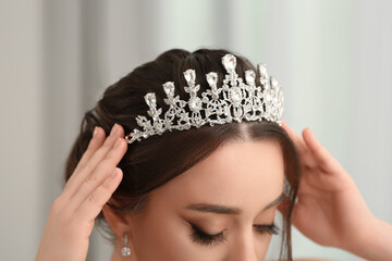 Beautiful young woman wearing luxurious tiara on blurred, closeup