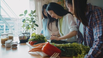 Three happy young women preparing asian food in the kitchen. Group of female friends enjoying their girls day at home cooking an healthy meal with vegetables and organic ingredients. lifestyle concept - Powered by Adobe