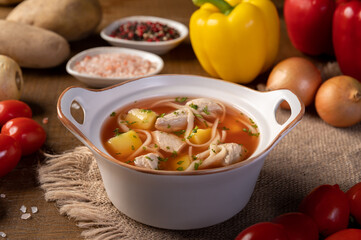 Delicious traditional romanian soup with pork meat, vegetables and noodles, close-up on wood background. Horizontal.