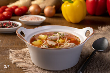 Traditional romanian soup with pork meat, vegetables and noodles, named ciorba de porc on wood background. Hotizontal.