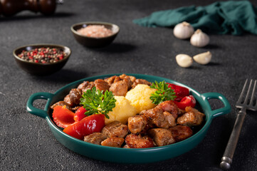 Delicious traditional romanian dish pomana porcului assortment of pork meat and sausages with mamaliga and pickled red peppers in a plate on dark backround. 