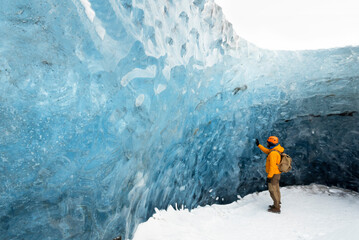  traveler finds himself detained in an impressive landscape of ice inside the Vatnajokull National Park, in Iceland. The dazzling ice formations and intricate patterns reveal the magnificent beauty o - obrazy, fototapety, plakaty