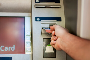 Hand of a man with a credit card, using an ATM. Man using an atm machine with his credit card.