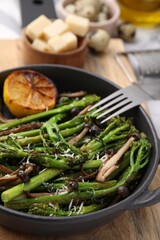 Tasty cooked broccolini, mushrooms and lemon on board, closeup