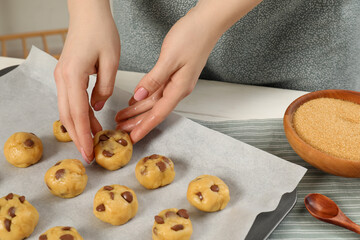 Obraz na płótnie Canvas Woman preparing chocolate chip cookies at white table in kitchen, closeup