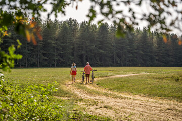 Fototapeta premium Mature man and his adult daughter walking with bikes