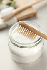 Bamboo toothbrush and jar of baking soda on table, closeup