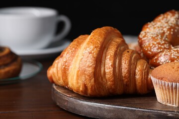 Freshly baked croissant and other pastries on wooden table, closeup. Space for text