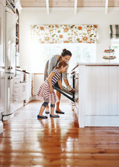 Food, mother with her child baking and in the kitchen of their home with a lens flare. Happy family or bonding time, bake or cook and woman with girl at the oven prepare a meal for lunch together