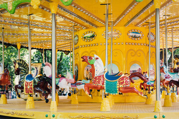 Merry carousel in the city park in the early morning. There is no one here. Carousels with horses are waiting for children. Concept: joy and entertainment for children. Selective focus.