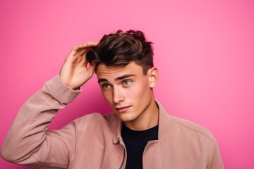 Medium shot portrait photography of a beautiful boy in his 20s making a gesture of i'm thinking with the finger on the head against a hot pink background. With generative AI technology