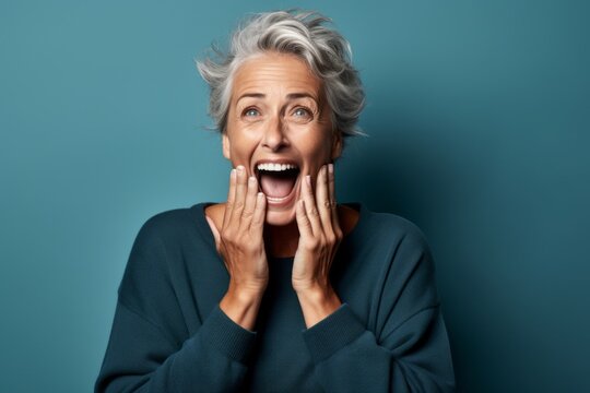 Headshot portrait photography of a satisfied mature woman making a surprise gesture by covering one's mouth against a teal blue background. With generative AI technology