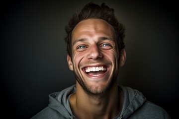 Headshot portrait photography of a happy boy in his 30s covering one eye against a metallic silver...