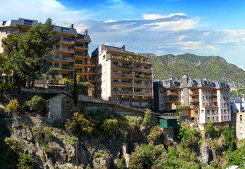 Picturesque cityscape of Andorra la Vella city. A Residential houses on the rocks and mountain range against the blue sky on a sunny afternoon. Andorra la Vella, the capital of principality of Andorra