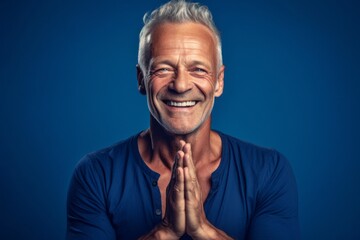 Medium shot portrait photography of a grinning mature man doing a yoga pose against a sapphire blue background. With generative AI technology