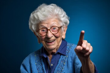 Headshot portrait photography of a joyful old woman making a i have an idea gesture with a finger up against a sapphire blue background. With generative AI technology