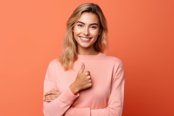 Medium shot portrait photography of a beautiful girl in her 20s showing a thumb up against a coral pink background. With generative AI technology