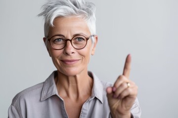 Close-up portrait photography of a satisfied mature woman making a i have an idea gesture with a finger up against a minimalist or empty room background. With generative AI technology