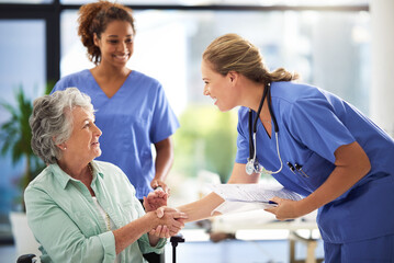 Handshake, nurse and senior woman in wheelchair with medical results and surgery success news. Hospital, healthcare and clinic with women and nursing staff with care and support of elderly person