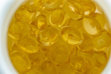 lots of yellow gelatin capsules on a light background. omega viramins, close-up, macro