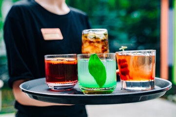 glasses alcohol cocktail set on a waiter tray outdoor cafe