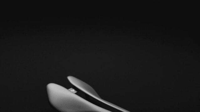 Black carbon road bicycle saddle on dark reflective background