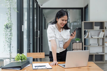 Beautiful woman in the office, happy and smiling business woman uses internet phone, female worker reads message and browses internet pages inside office building