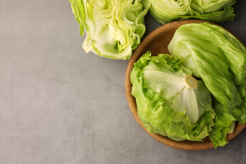 Fresh green cut and whole iceberg lettuce heads on grey table, flat lay. Space for text